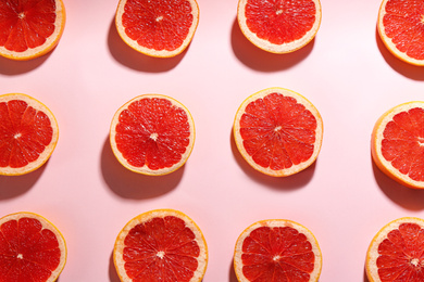 Photo of Tasty ripe grapefruit slices on pink background, flat lay