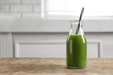 Photo of Bottle with delicious detox juice on wooden table