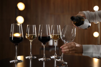 Waitress pouring wine into glass in restaurant, closeup