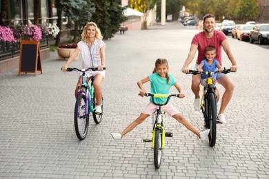Happy family with children riding bicycles in city