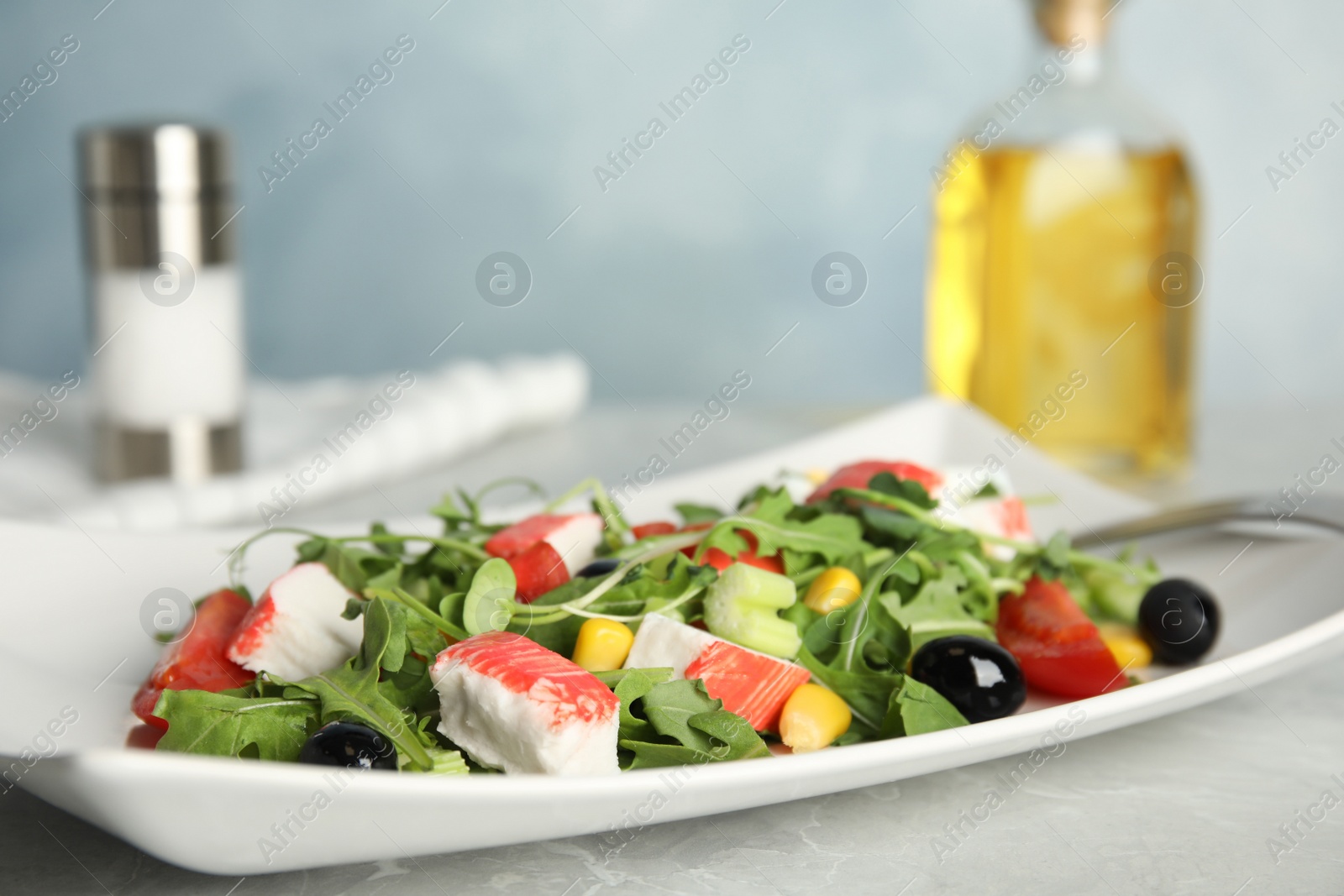 Photo of Tasty crab stick salad served on grey marble table, closeup