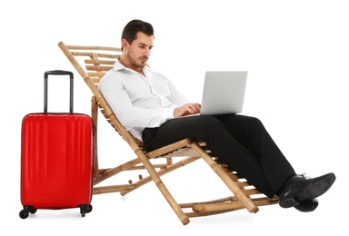 Photo of Young businessman with laptop and suitcase on sun lounger against white background. Beach accessories