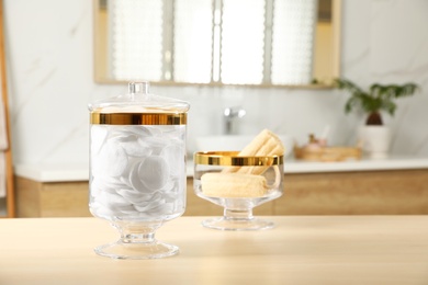 Jars with cotton pads and loofah sponges on table in bathroom