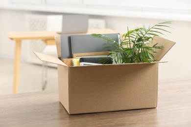 Photo of Unemployment problem. Box with worker's personal belongings on table in office