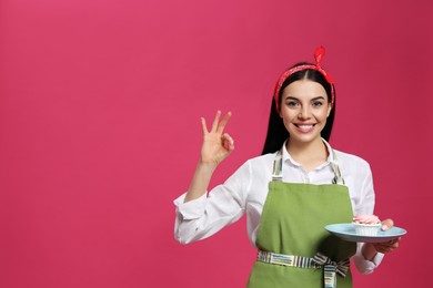 Photo of Young housewife with tasty cupcake on pink background, space for text