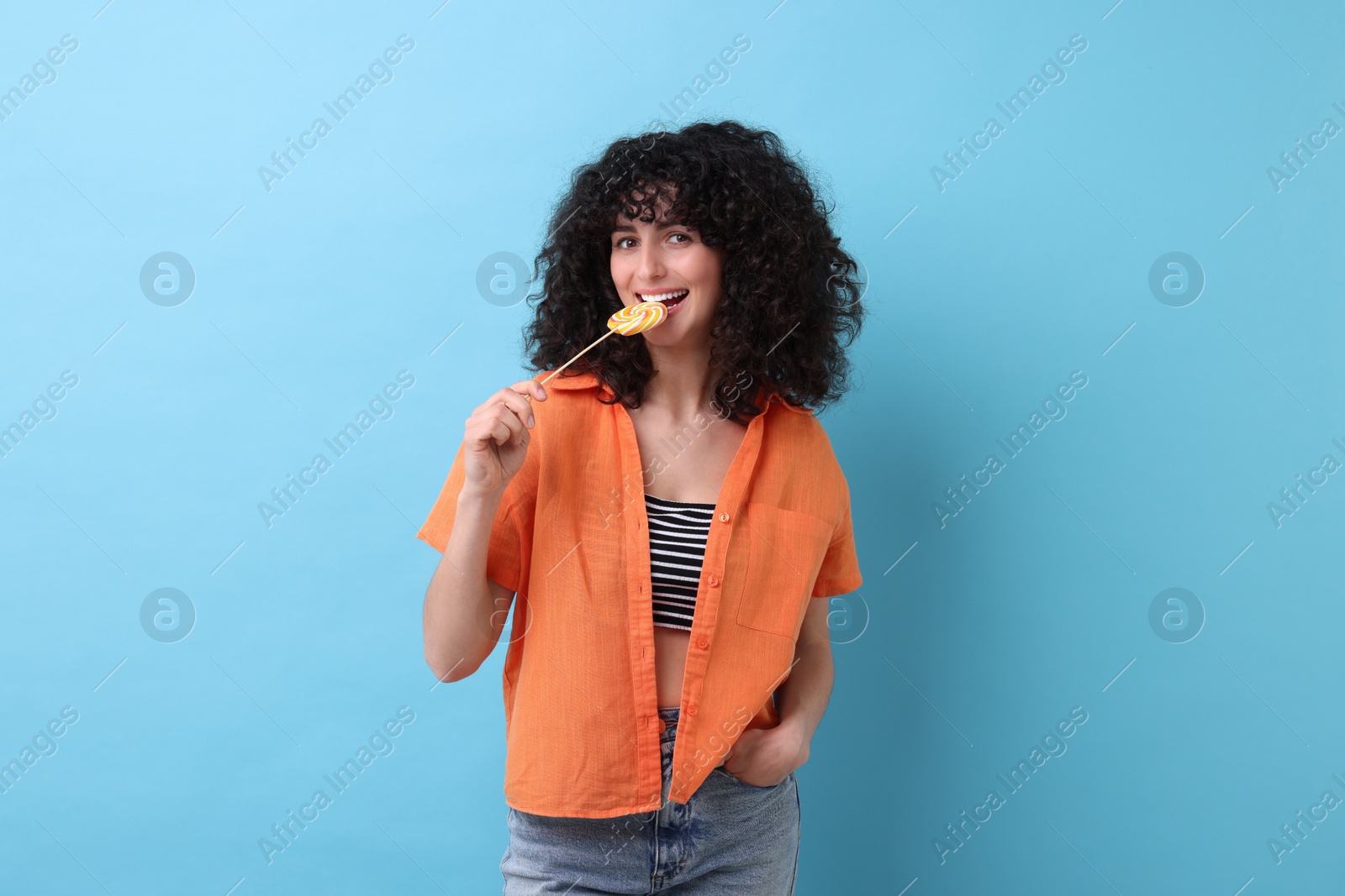 Photo of Beautiful woman with lollipop on light blue background