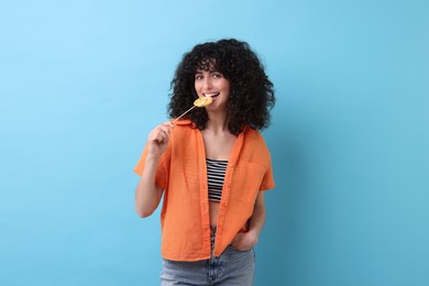 Beautiful woman with lollipop on light blue background