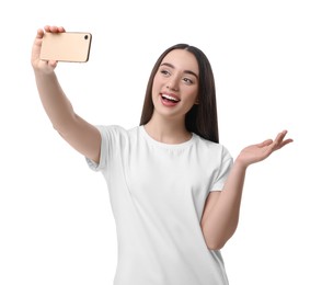 Smiling young woman taking selfie with smartphone on white background