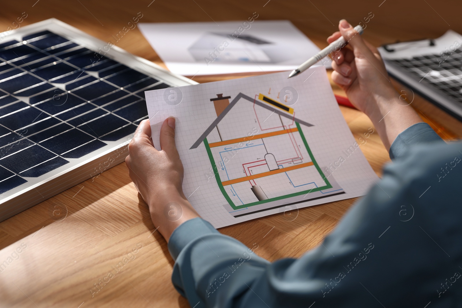 Photo of Woman working on house project with solar panels at table in office, closeup