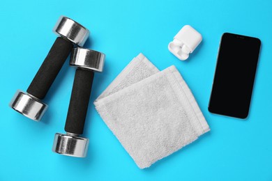 Flat lay composition with dumbbells on light blue background