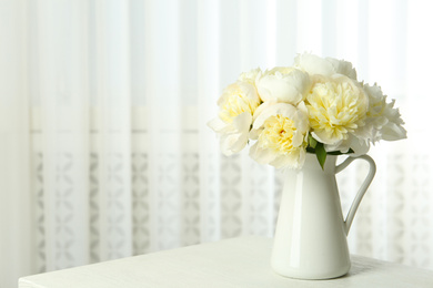 Bouquet of beautiful peonies in vase on white table. Space for text