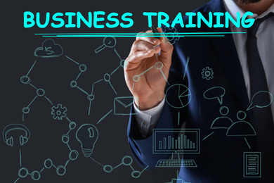 Image of Man pointing at virtual screen with inscription BUSINESS TRAINING on dark background, closeup 