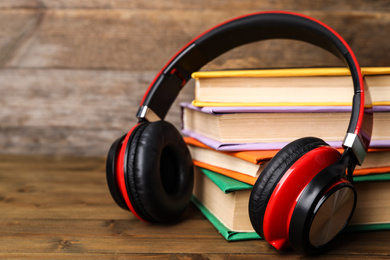 Photo of Books and modern headphones on wooden table, closeup
