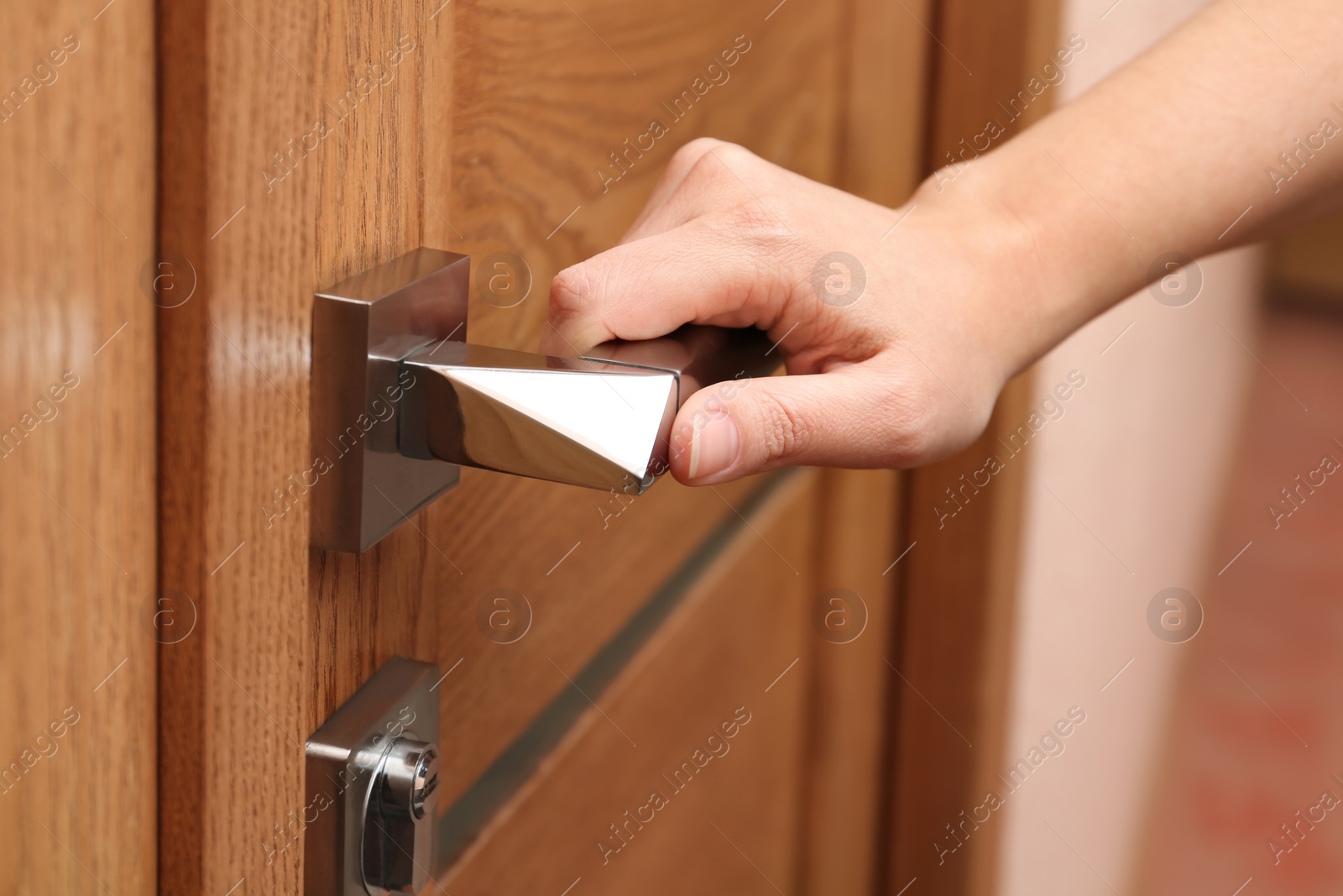 Photo of Woman opening wooden door indoors, closeup view