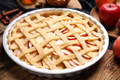 Photo of Raw traditional English apple pie in baking dish on wooden table, closeup