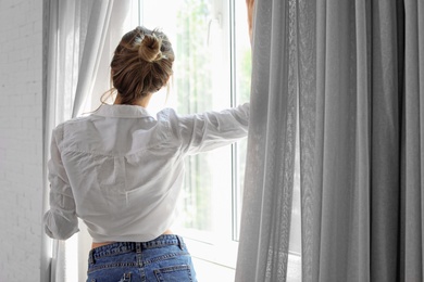 Photo of Young happy woman near window at home. Lazy morning