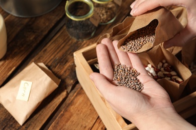 Photo of Woman pouring radish seeds from paper bag into hand, closeup. Vegetable planting