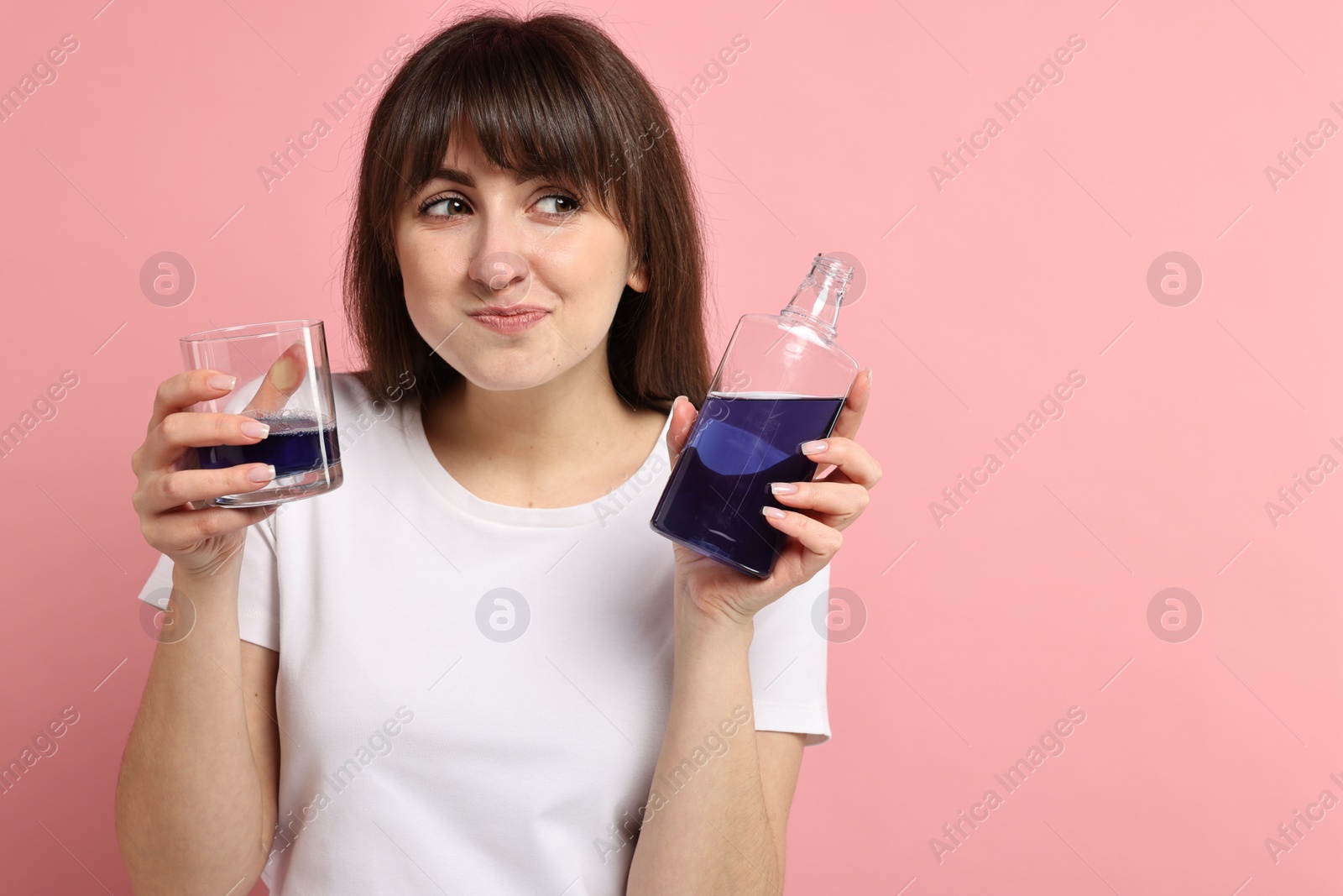 Photo of Young woman using mouthwash on pink background. Space for text