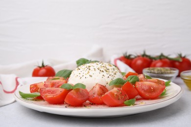 Photo of Tasty salad Caprese with mozarella, tomatoes and basil on light table, closeup