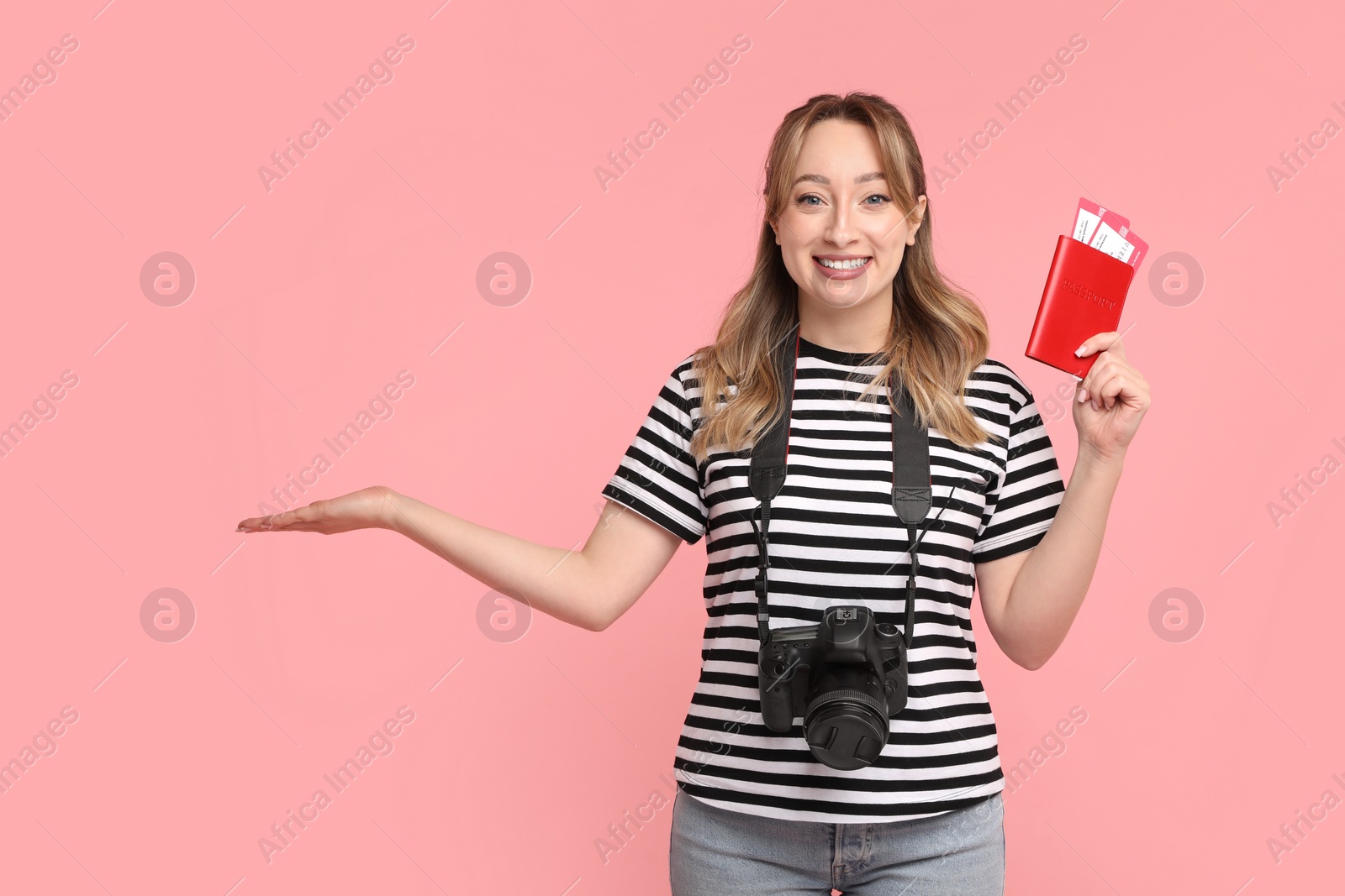 Photo of Happy young woman with passport, ticket and camera on pink background