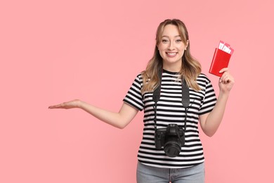 Photo of Happy young woman with passport, ticket and camera on pink background