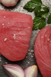 Raw tuna fillets with salt, parsley and shallot on gray table, flat lay