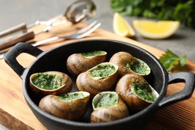 Photo of Delicious cooked snails in baking dish on table, closeup