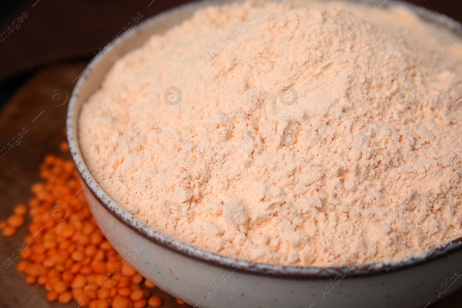 Photo of Bowl of lentil flour and seeds on wooden table, closeup