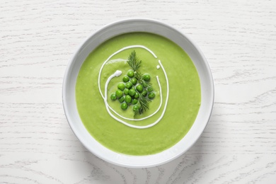 Photo of Fresh vegetable detox soup made of green peas in dish on wooden table, top view