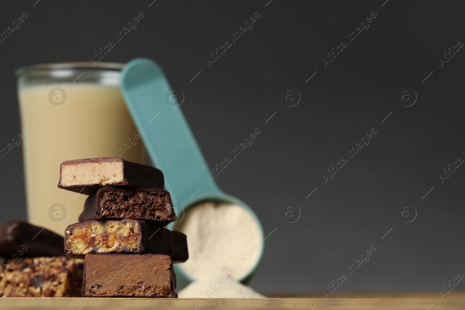 Photo of Different energy bars, protein cocktail and powder on wooden table, closeup. Space for text