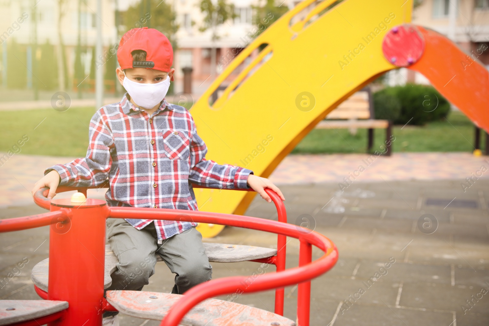 Photo of Little boy with medical face mask on playground during covid-19 quarantine