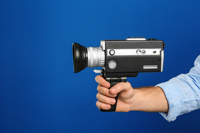 Photo of Man with vintage video camera on blue background, closeup of hand