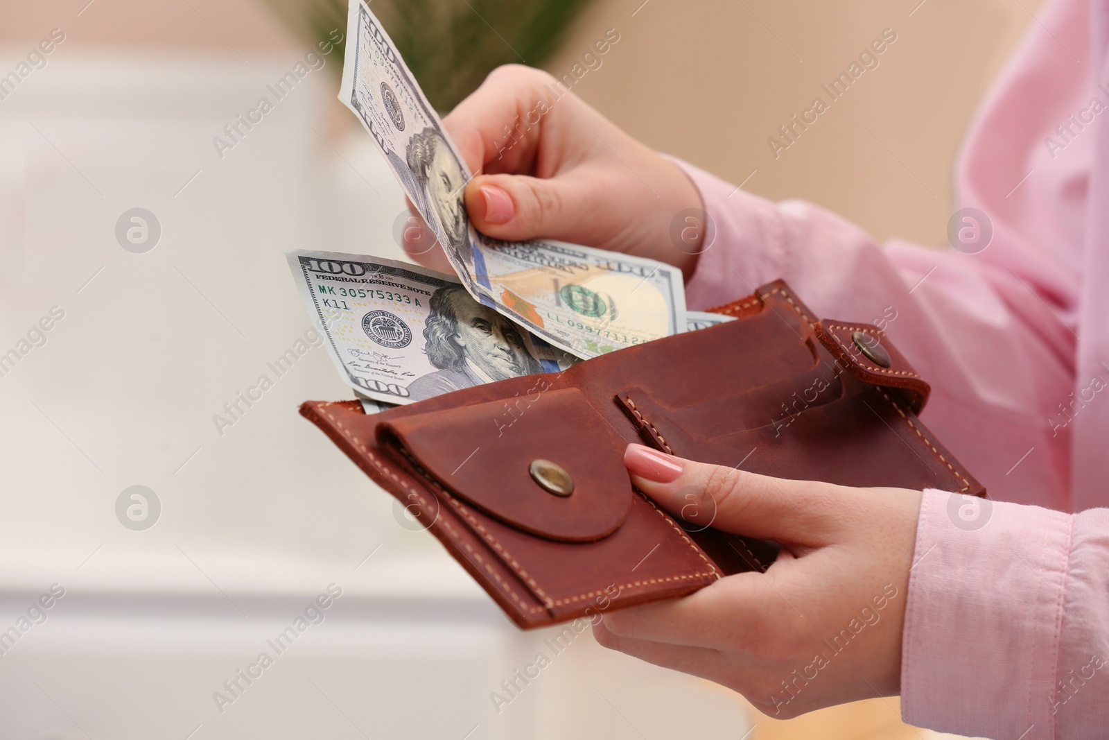 Photo of Woman counting dollar bills indoors, closeup. Money exchange