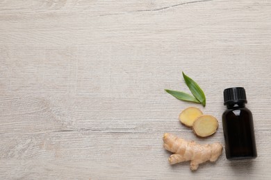 Photo of Glass bottle of essential oil and ginger root on white wooden table, flat lay. Space for text