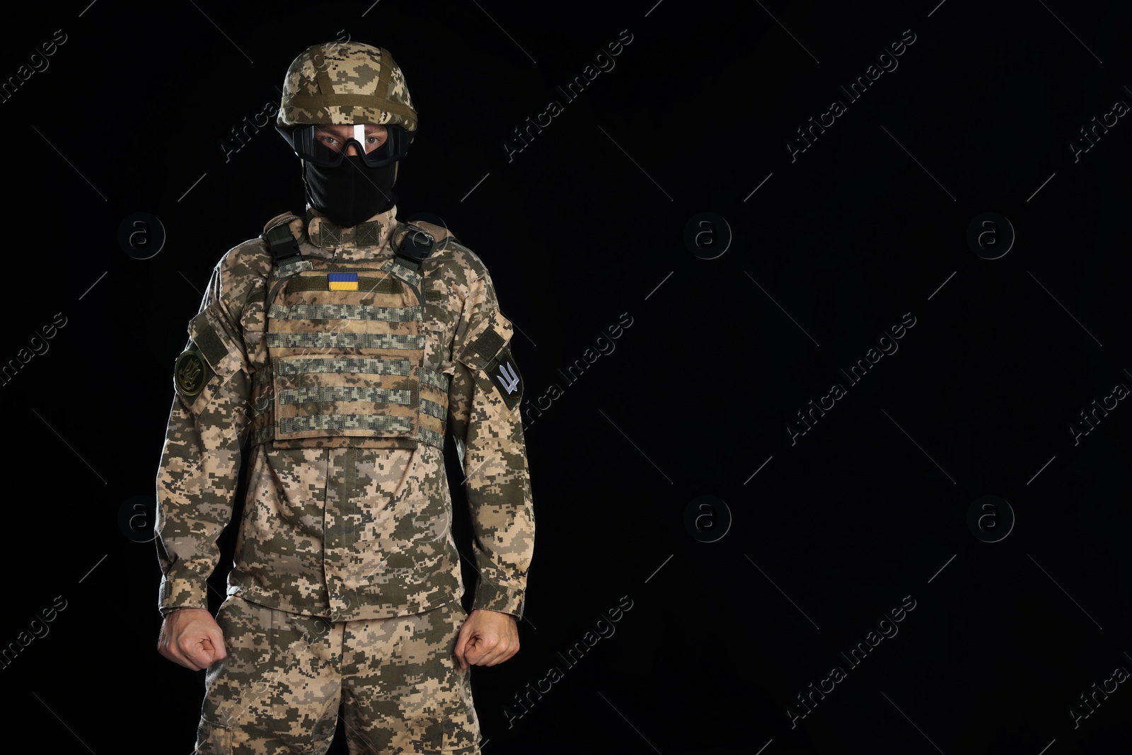 Photo of Soldier in Ukrainian military uniform, tactical goggles and balaclava on black background. Space for text