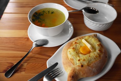 Fresh delicious Adjarian khachapuri with cheese and egg on wooden table