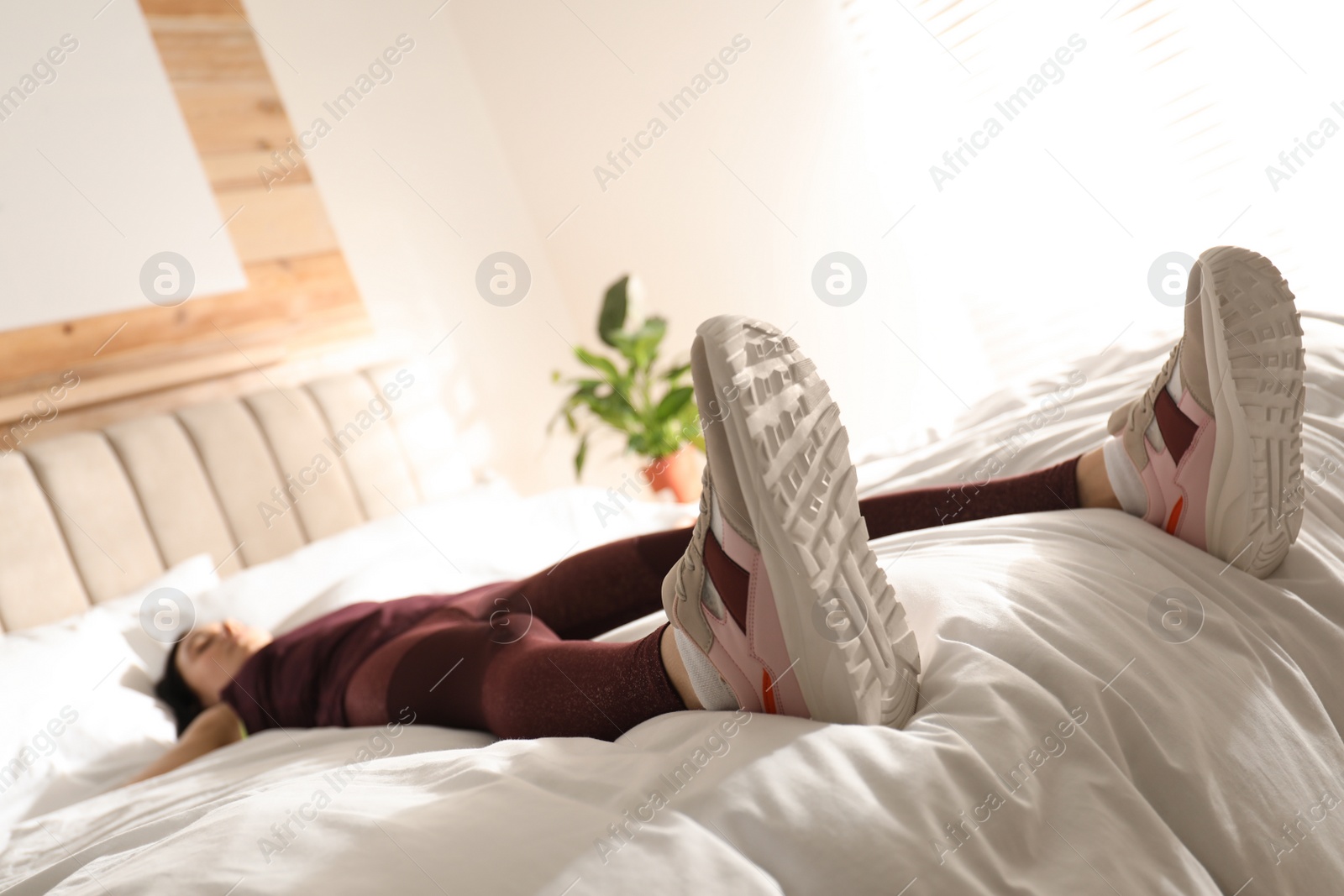 Photo of Lazy young woman sleeping on bed instead of morning training, focus on legs