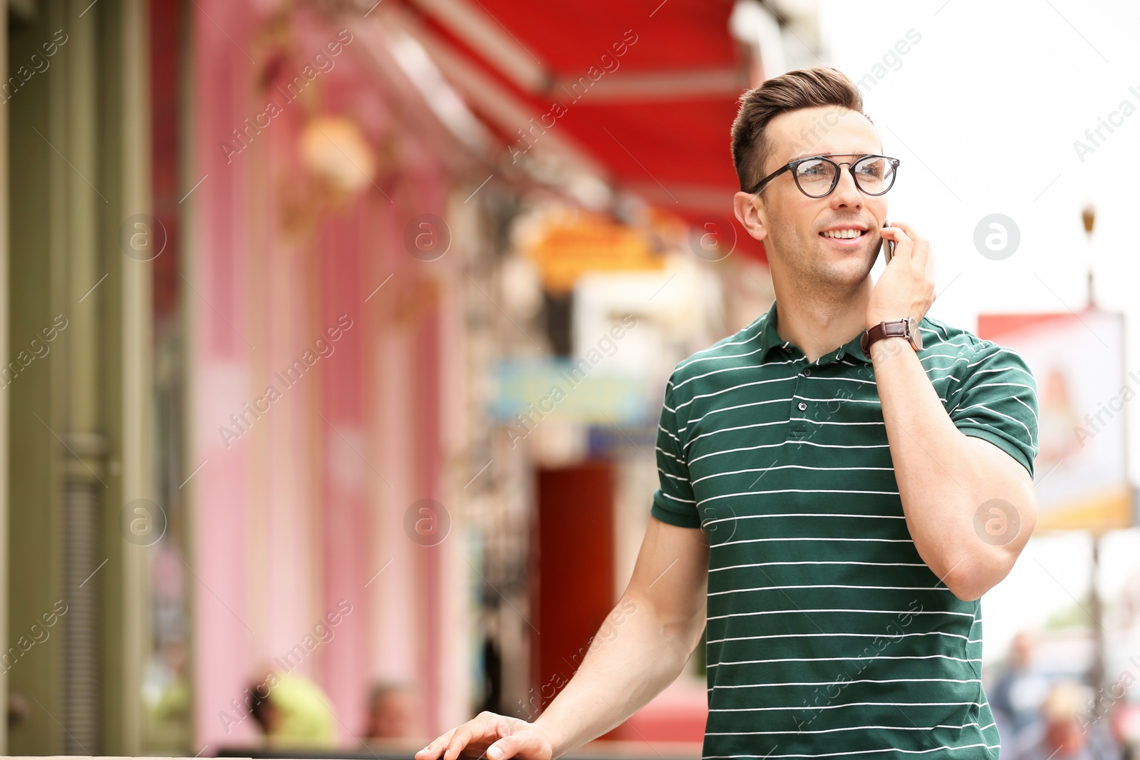 Photo of Attractive young man talking on phone outdoors