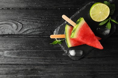 Photo of Slate board with juicy watermelon, ice and lime on black wooden table, flat lay. Space for text