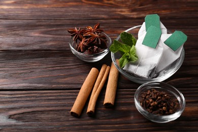 Tea bags and ingredients on wooden table. Space for text