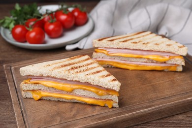 Photo of Delicious grilled sandwiches with ham and cheese on wooden table. Space for text