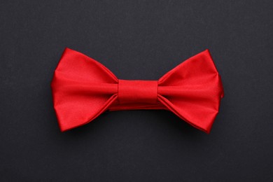 Stylish red bow tie on black background, top view