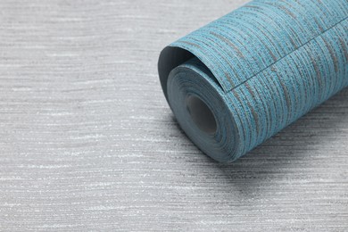 Light blue wallpaper roll on grey sample, space for text