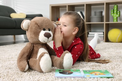 Photo of Cute little girl playing with teddy bear at home