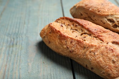 Photo of Tasty buckwheat baguettes on light blue wooden table, closeup. Space for text