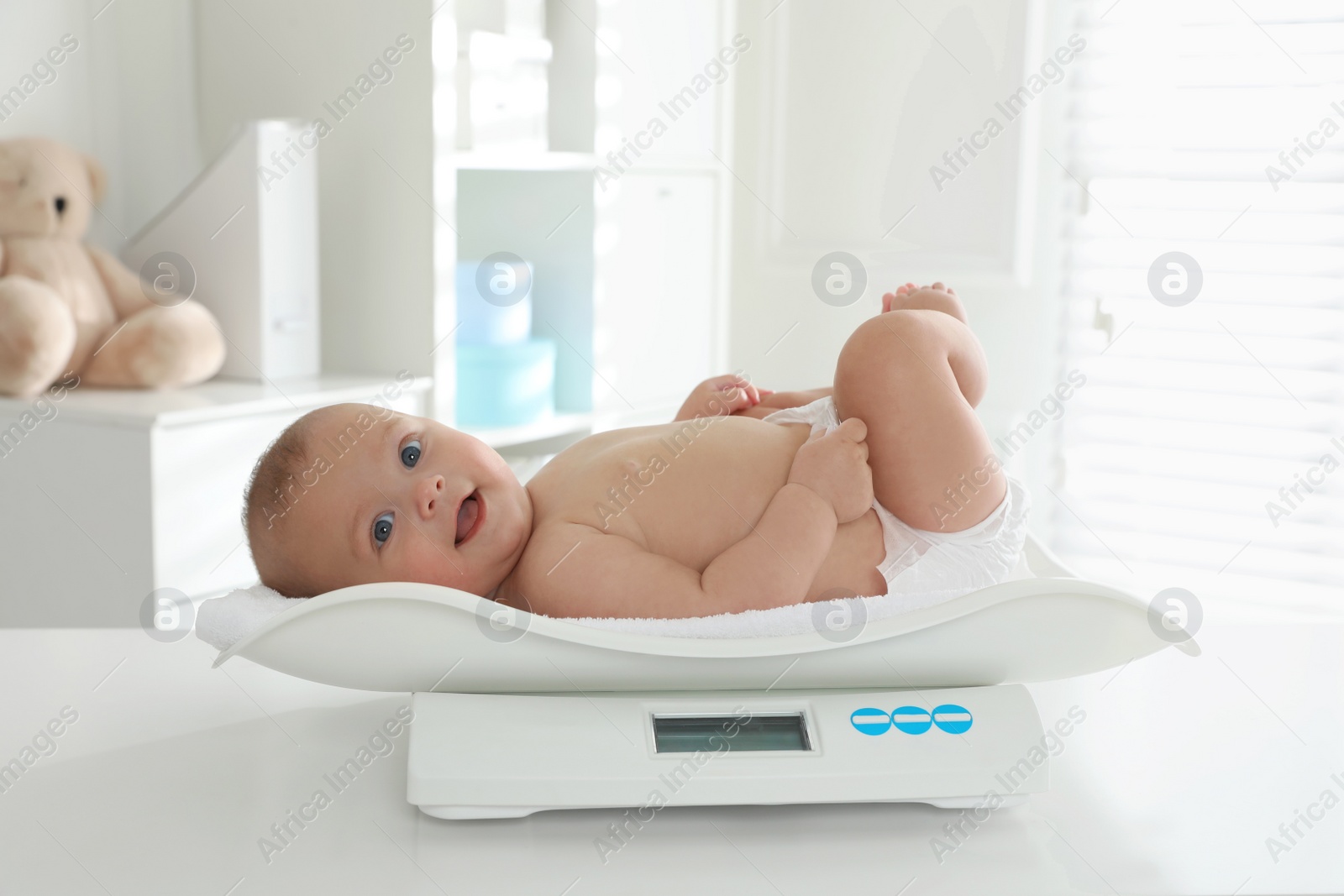 Photo of Cute little baby lying on scales in clinic