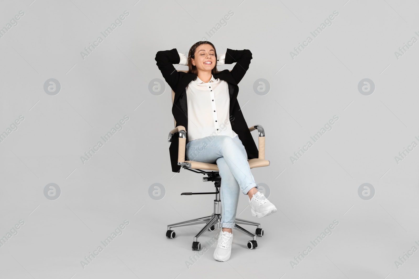 Photo of Young woman relaxing in comfortable office chair on grey background