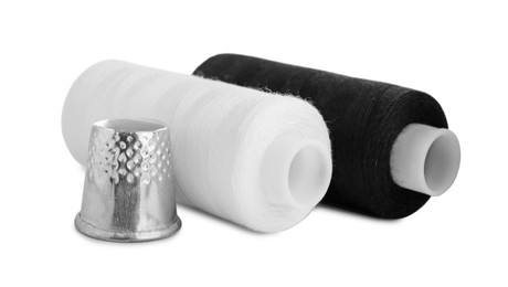 Photo of Thimble and spools of sewing threads isolated on white