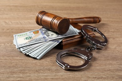 Photo of Judge's gavel, money and handcuffs on wooden table