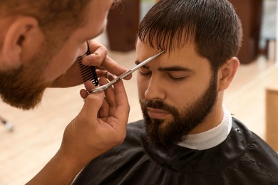 Photo of Professional hairdresser working with client in barbershop, closeup